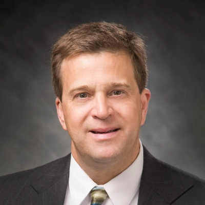 Chiropractor Kelly Towne Smiling In Front Of Grey Background